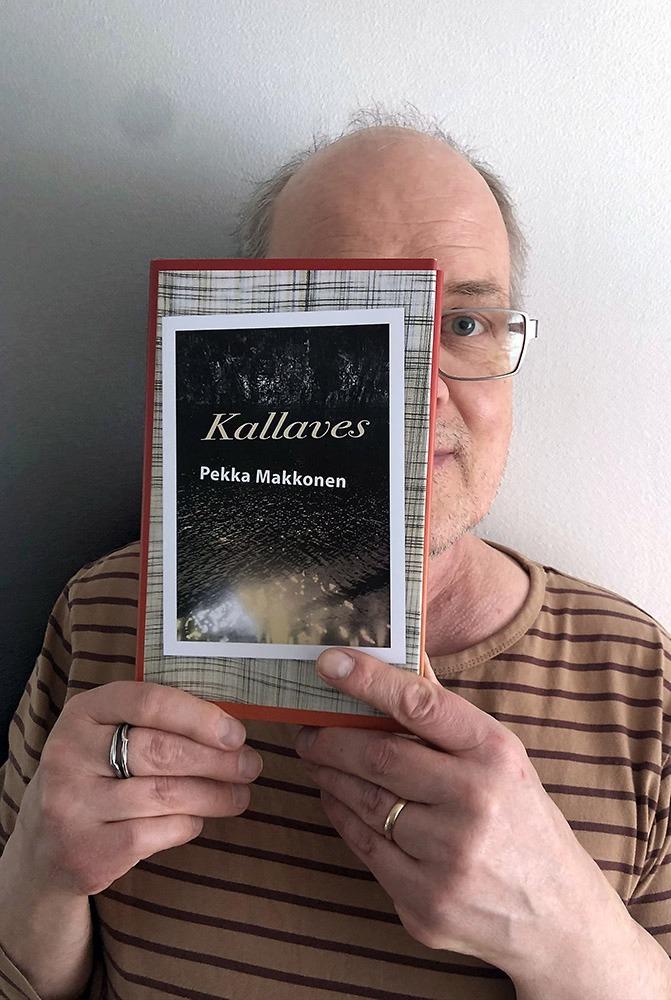 Silmälasipäinen mies pitelee kirjaa puolittain kasvojensa edessä. Kirjan kannessa lukee Kallaves Pekka Makkonen. Miehellä on yllään raidallinen t-paita ja vasemmassa nimettömässä sormus.
